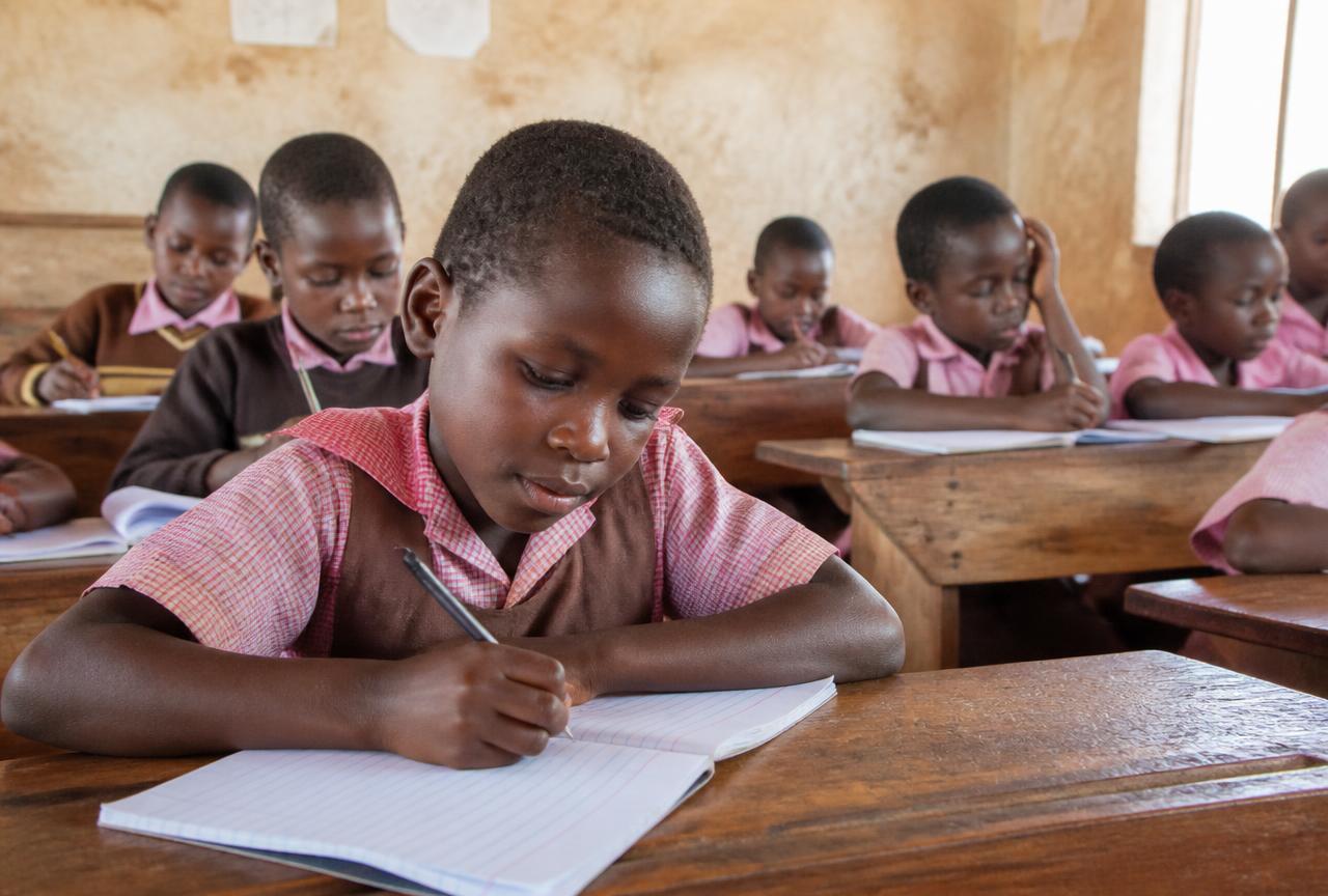 Children writing in a classroom supported by ACBF education programs